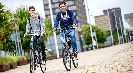 Two students on a bike on campus