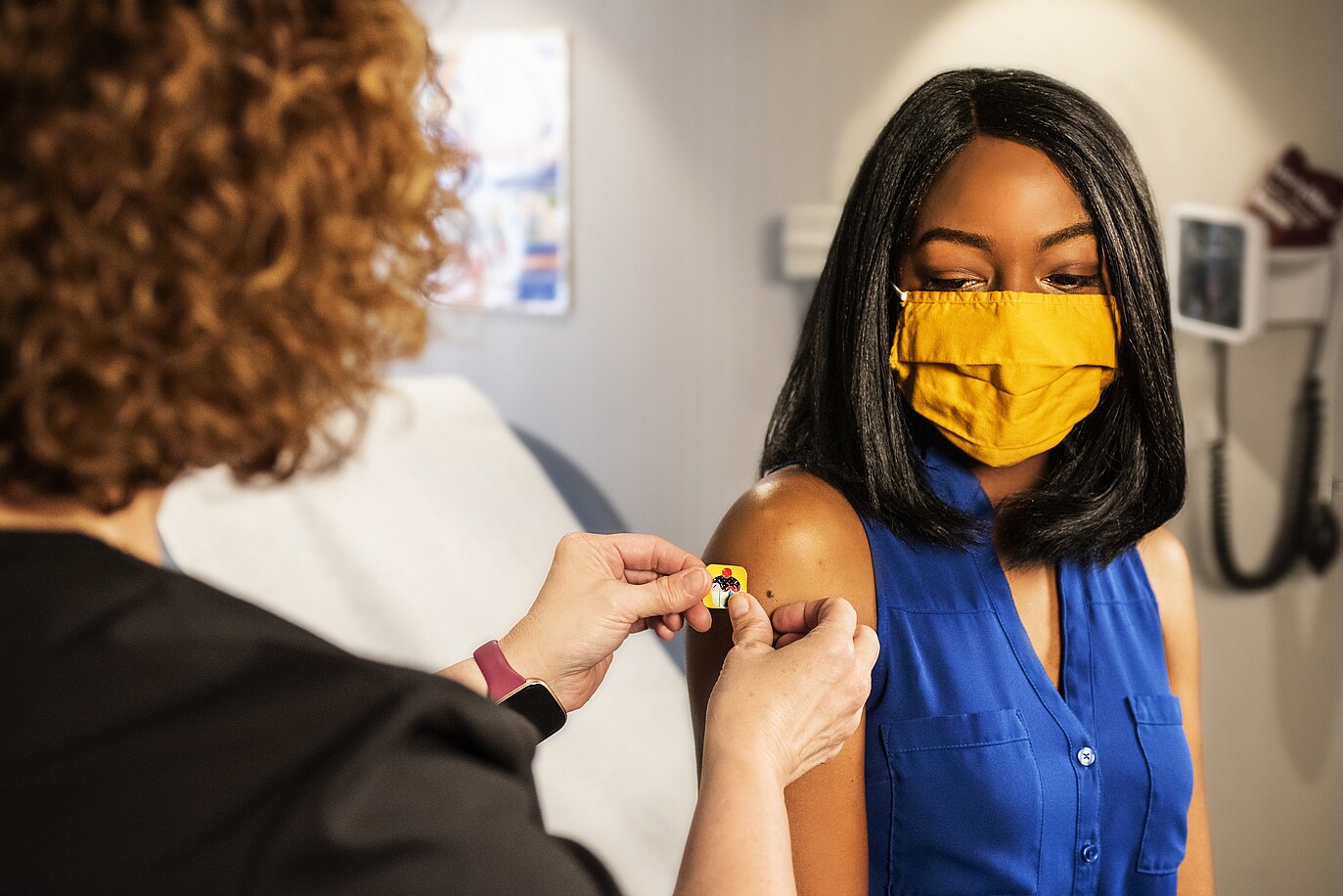 An image shows a woman in the mask being vaccinated 