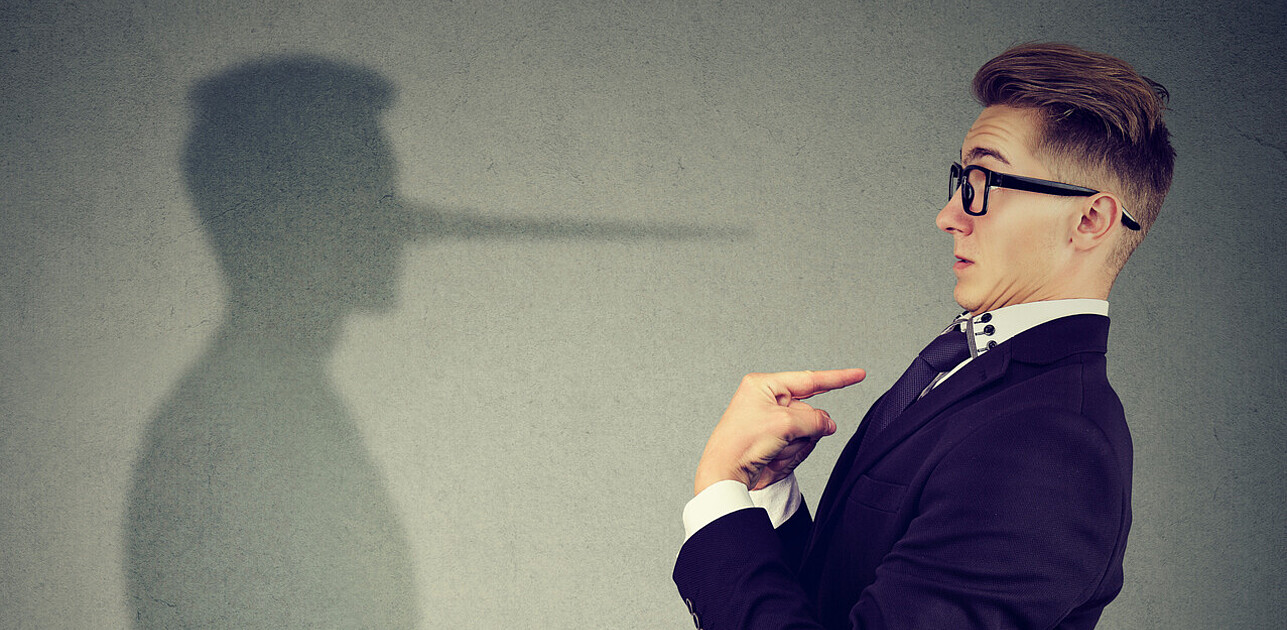 An image shows a surprised man pointing at himself with a dishonest shadow at the background