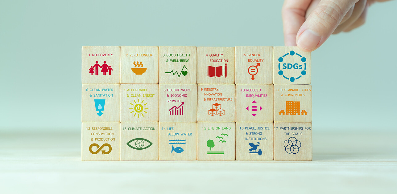 Wooden cubes stacked, each displaying symbols representing key Sustainable Development Goals (SDGs) prioritized by a multinational company.