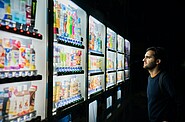 a man looking at different vending machines, deciding what to chose