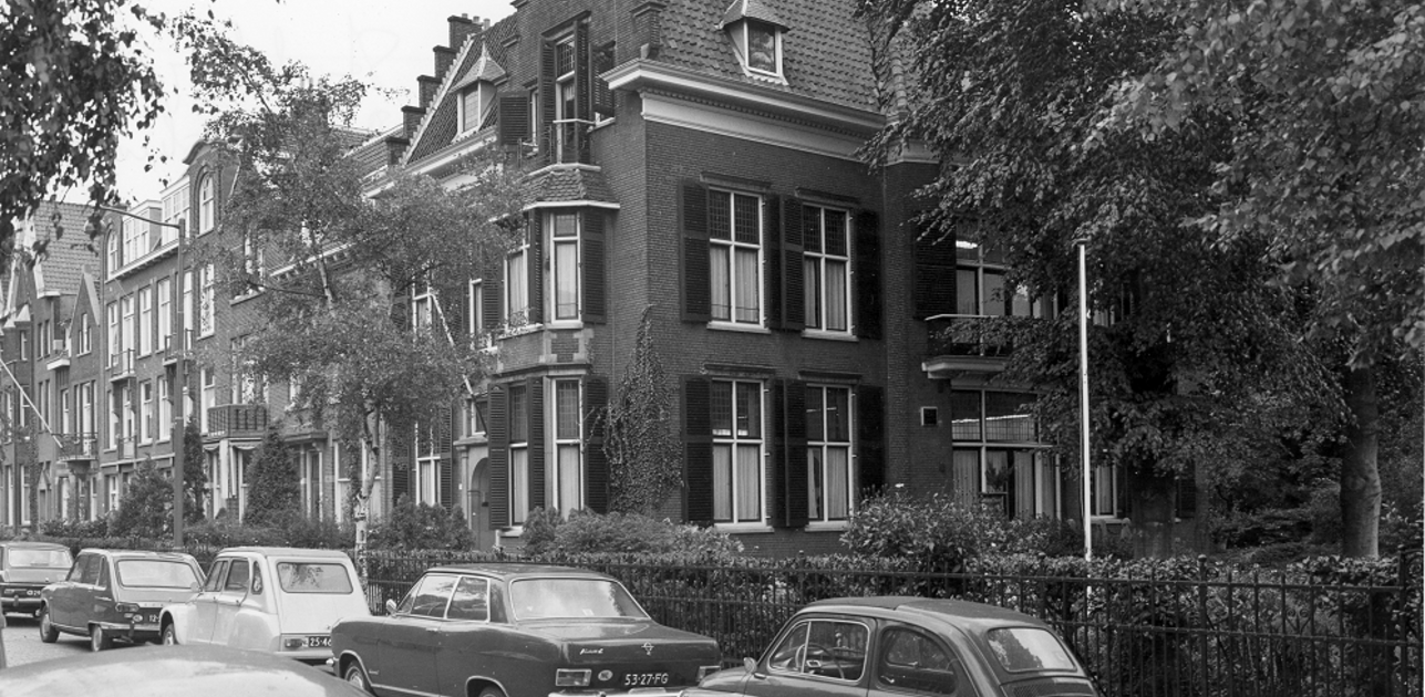 An old black and white photo shows Rotterdam street with houses and cars
