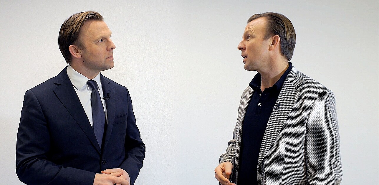 Image of a man engaging in conversation with another version of himself: one dressed elegantly and the other in casual attire.