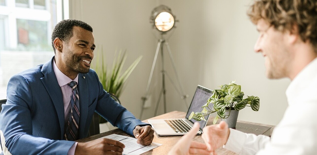 An insurance agent discussing and outlining the details of an insurance policy to a client at a desk.