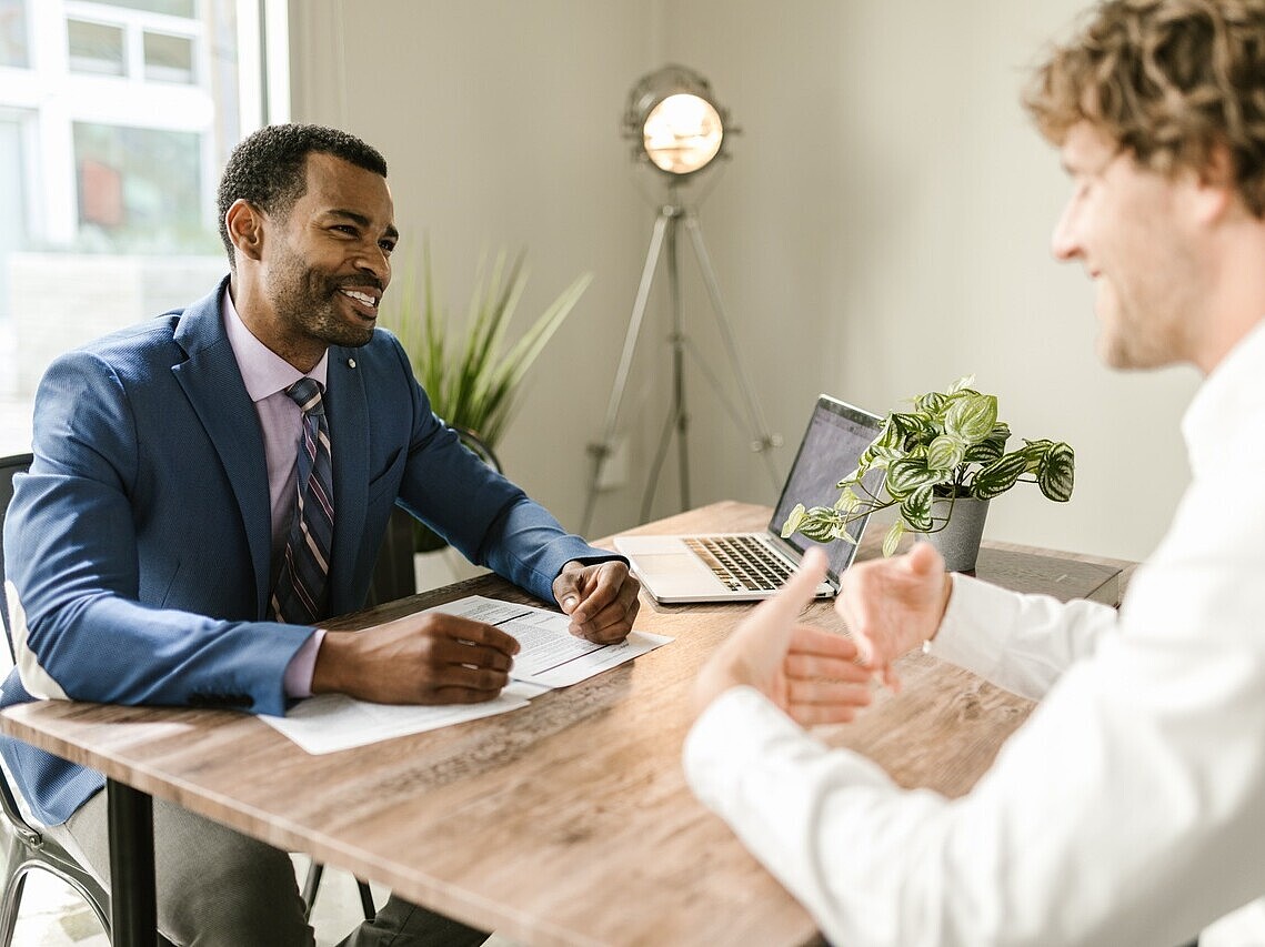 An insurance agent discussing and outlining the details of an insurance policy to a client at a desk.