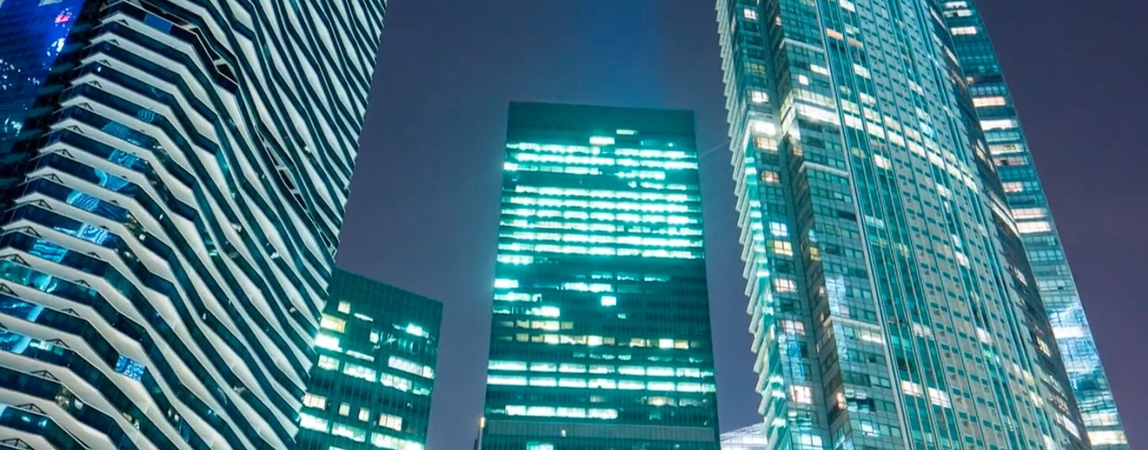 Skyscrapers illuminated by office lights against the night sky.