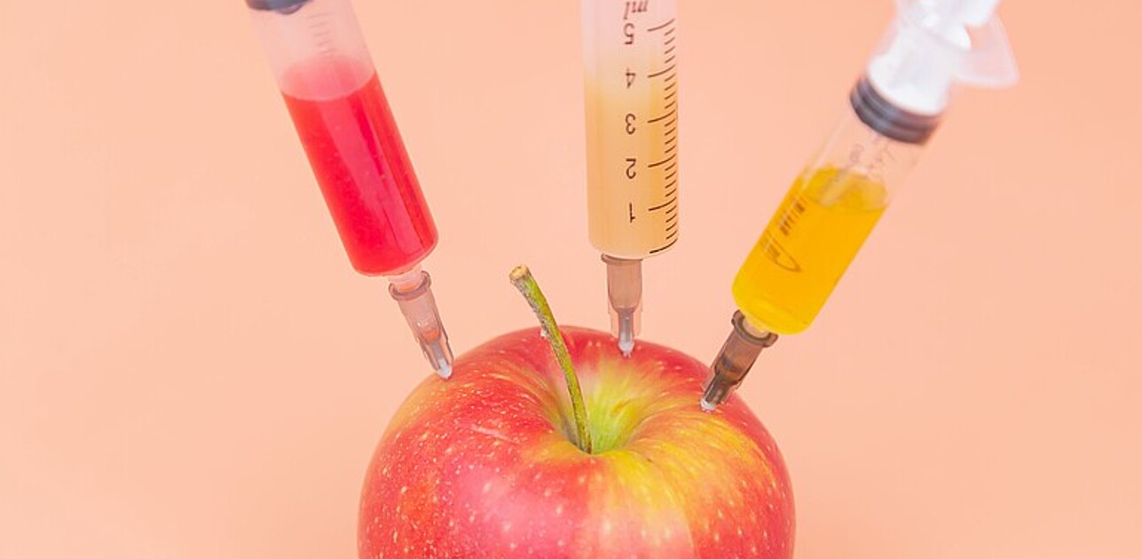 Three different injections sticking in a red apple.