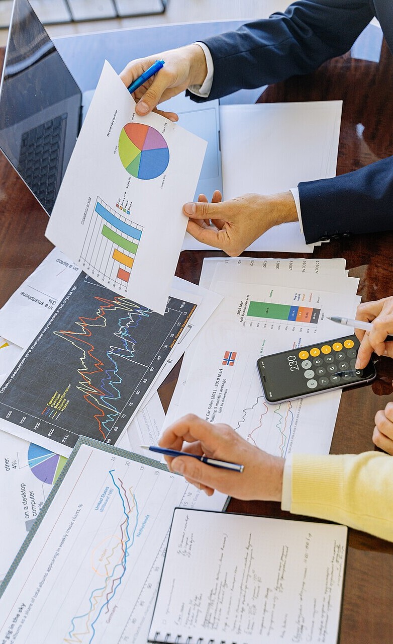 Insurance analysts intently studying data charts and graphs on computer screens and printed reports.