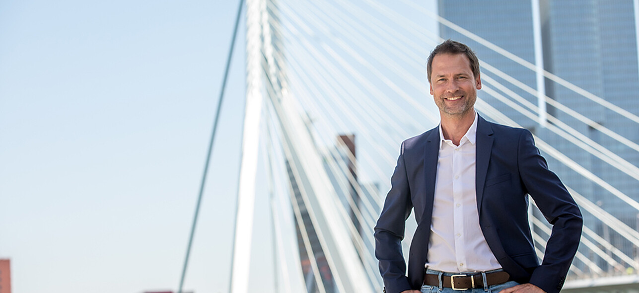 Elegant man posing in front of the Erasmus Bridge in Rotterdam