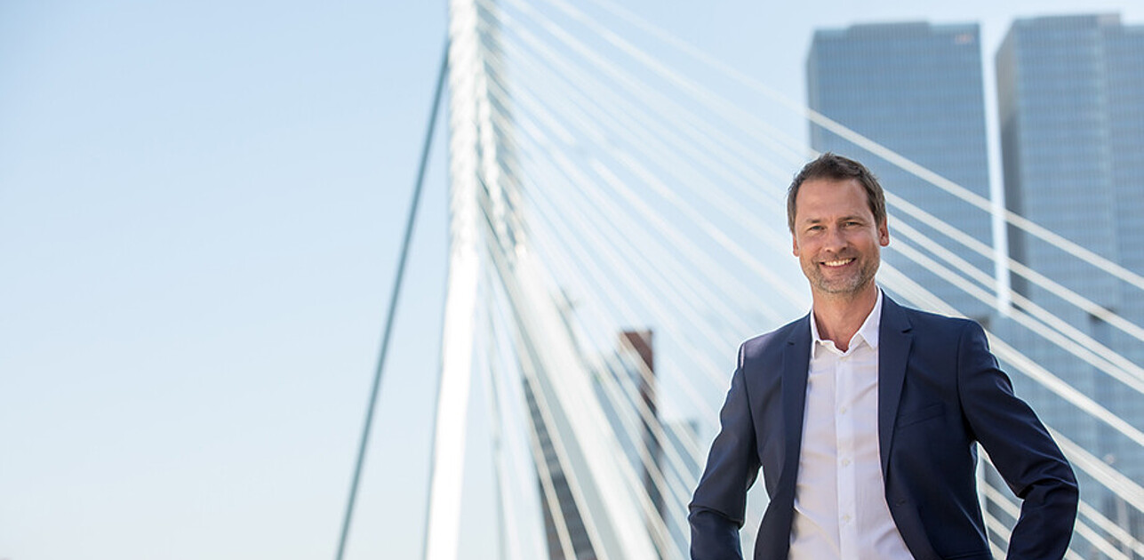 Elegant man posing in front of the Erasmus Bridge in Rotterdam