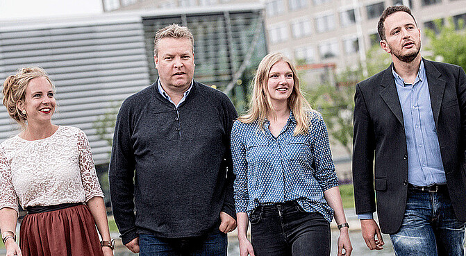 Four PhD students walking next to each other on campus