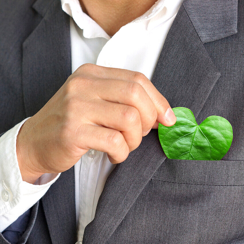 An image shows a socially responsible man in a business suit holding a heart shaped leaf