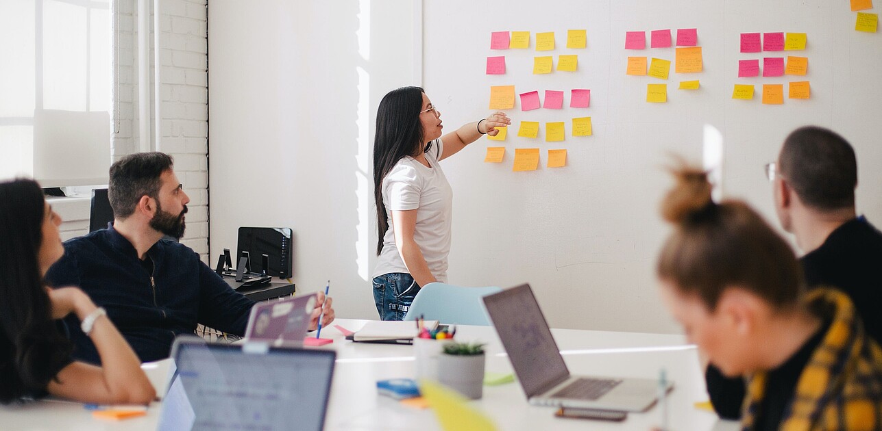 People in an office working as a team with post-its on a whiteboard