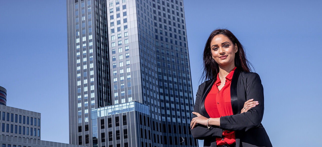 Young woman posing in front of De Rotterdam, Rotterdam's iconic modern skyscraper.
