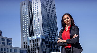 Young woman posing in front of De Rotterdam, Rotterdam's iconic modern skyscraper.