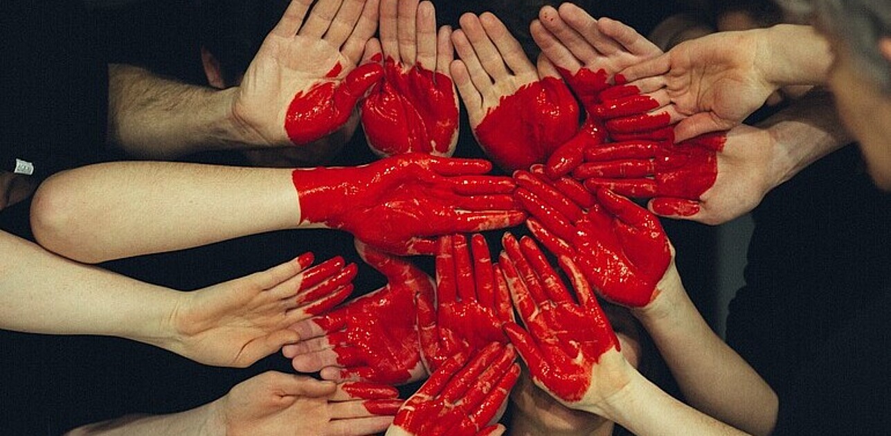 Multiple hands painted with a red heart.