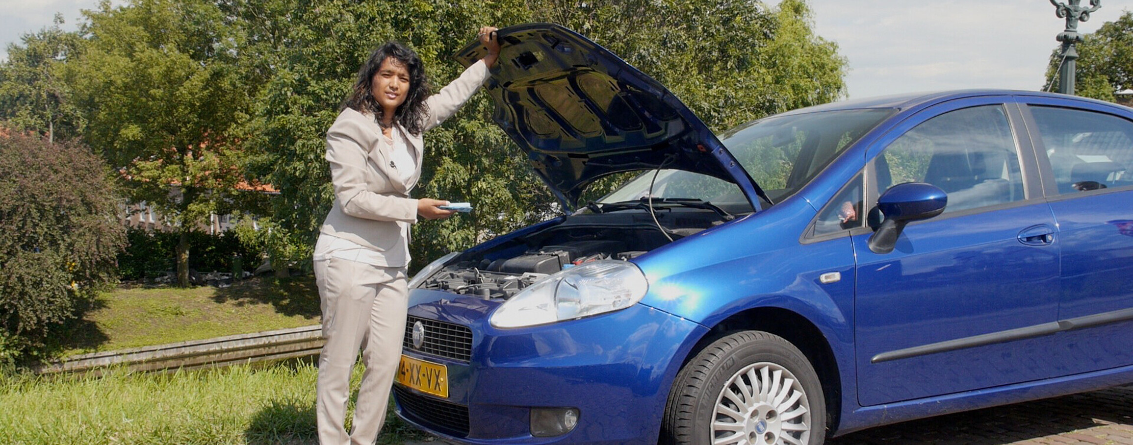 A woman looking at the engine of her car