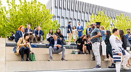 Student sitting down and having fun in front of the Erasmus University campus lake 