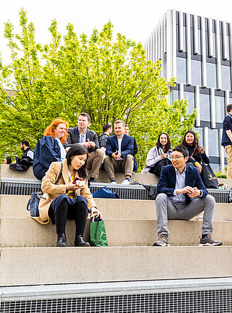 Student sitting down and having fun in front of the Erasmus University campus lake 