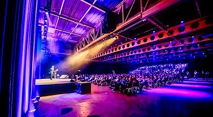 A speaker standing on a huge stage lit by spotlights