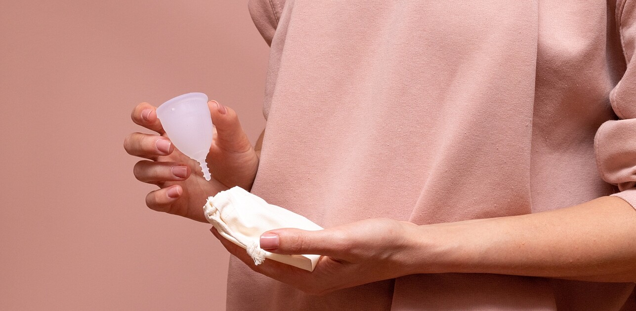 An image shows a woman holding a menstrual cup