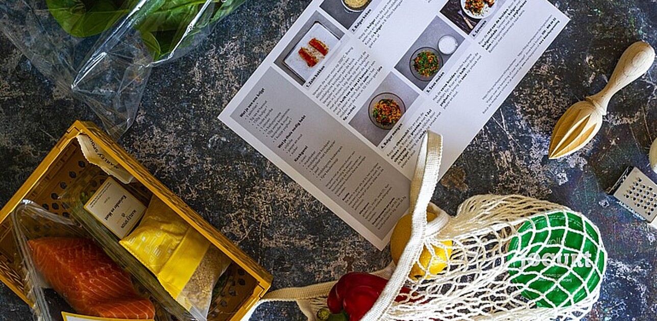 Fresh foodbox with ingredients and recipe on stone table.