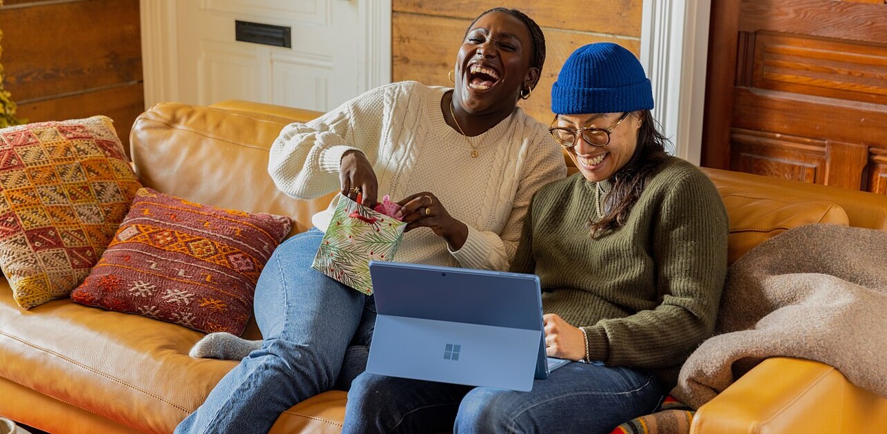 Two people laughing together whilst sitting on a couch