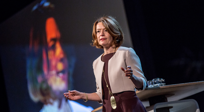 Woman standing at a podium, giving a speech at an event at Rotterdam School of Management. The woman is looking at the audience and speaking with passion.