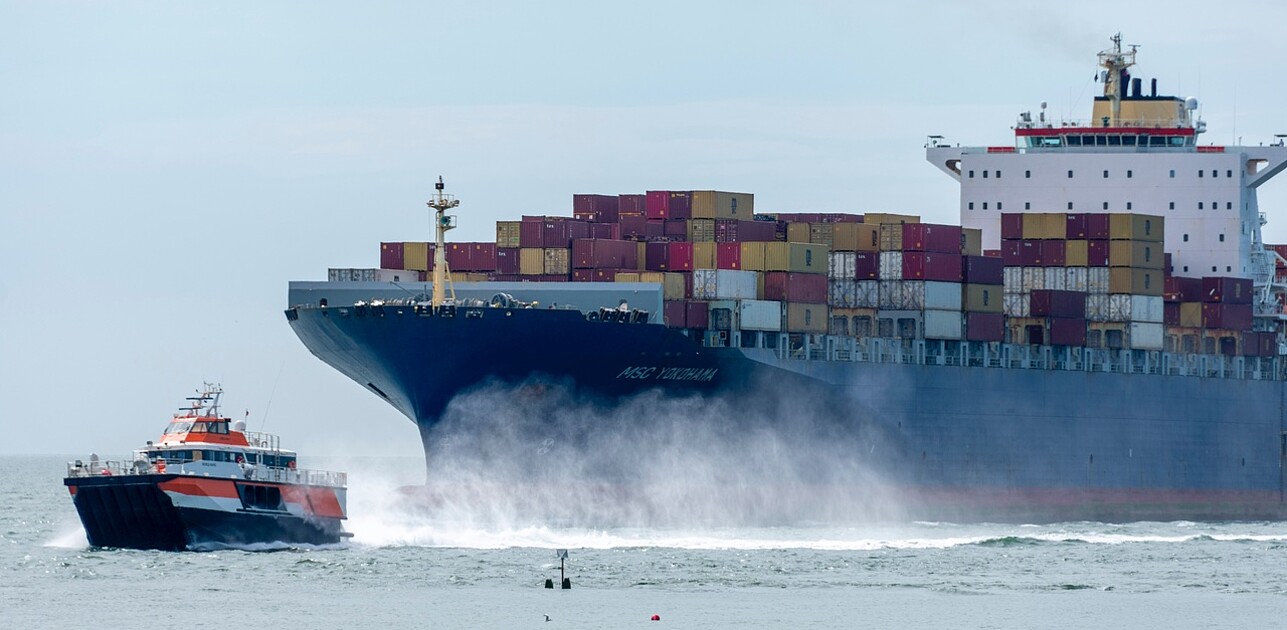 a containership is being pulled by a smaller ship