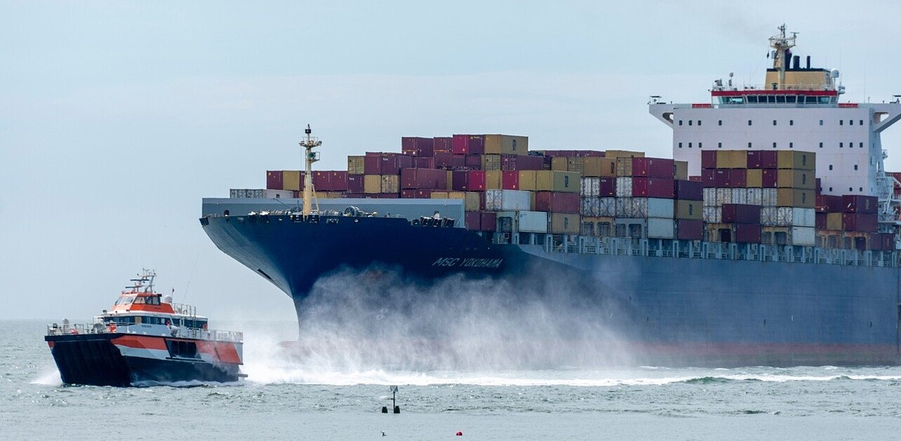a containership is being pulled by a smaller ship