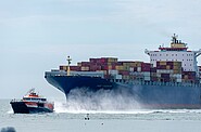 a containership being pulled by a smaller ship