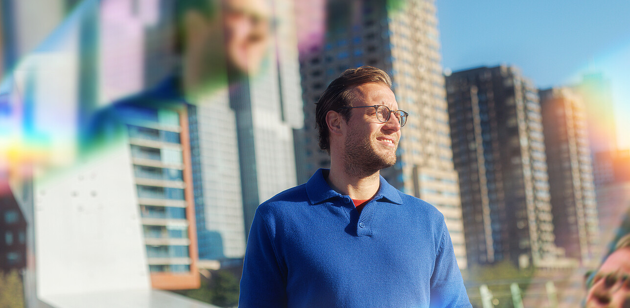 Een man die voor de skyline van Rotterdam staat met prisma's om hem heen.