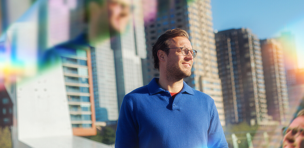 A man standing in front of the skyline of Rotterdam with prisms around him.