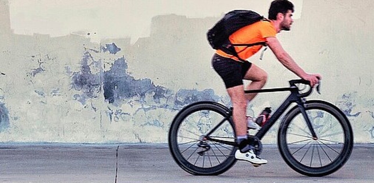 Male bike driver in front of white wall.