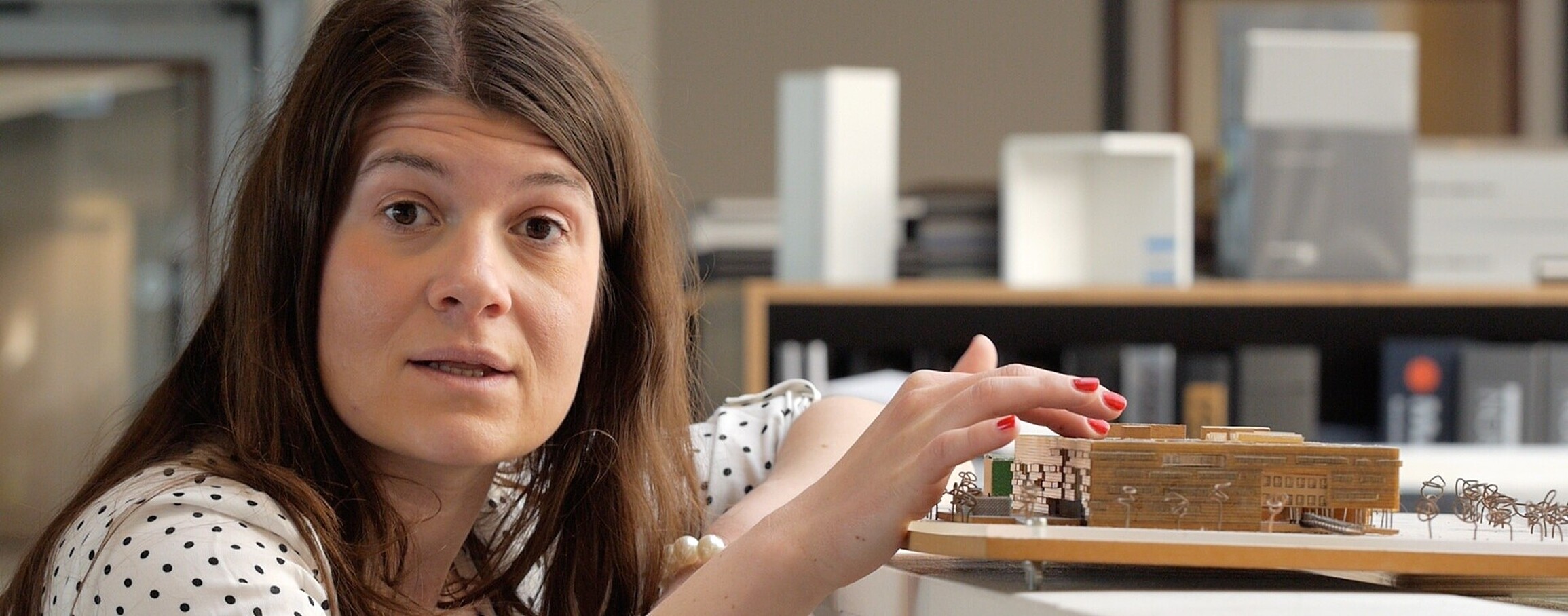 Woman crouches next to miniature set of several buildings