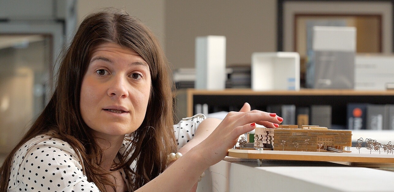 Woman crouches next to miniature set of several buildings