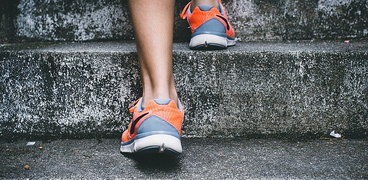 Legs of a person walking up the stairs in nike running-shoes.