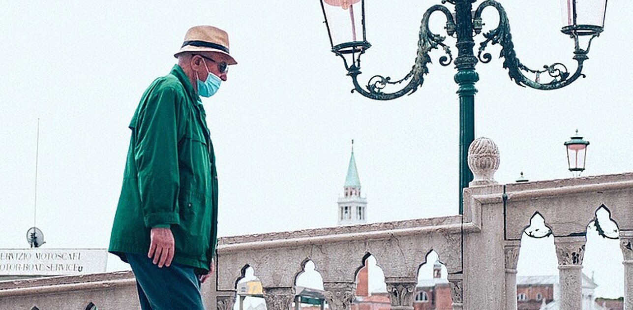 Elderly man walking on public place with a mask on.