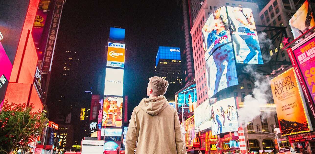 Man in times square New York looking at billboards