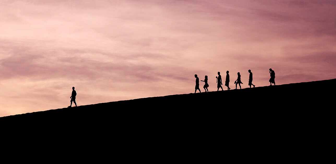 silhouettes of people walking on mountain