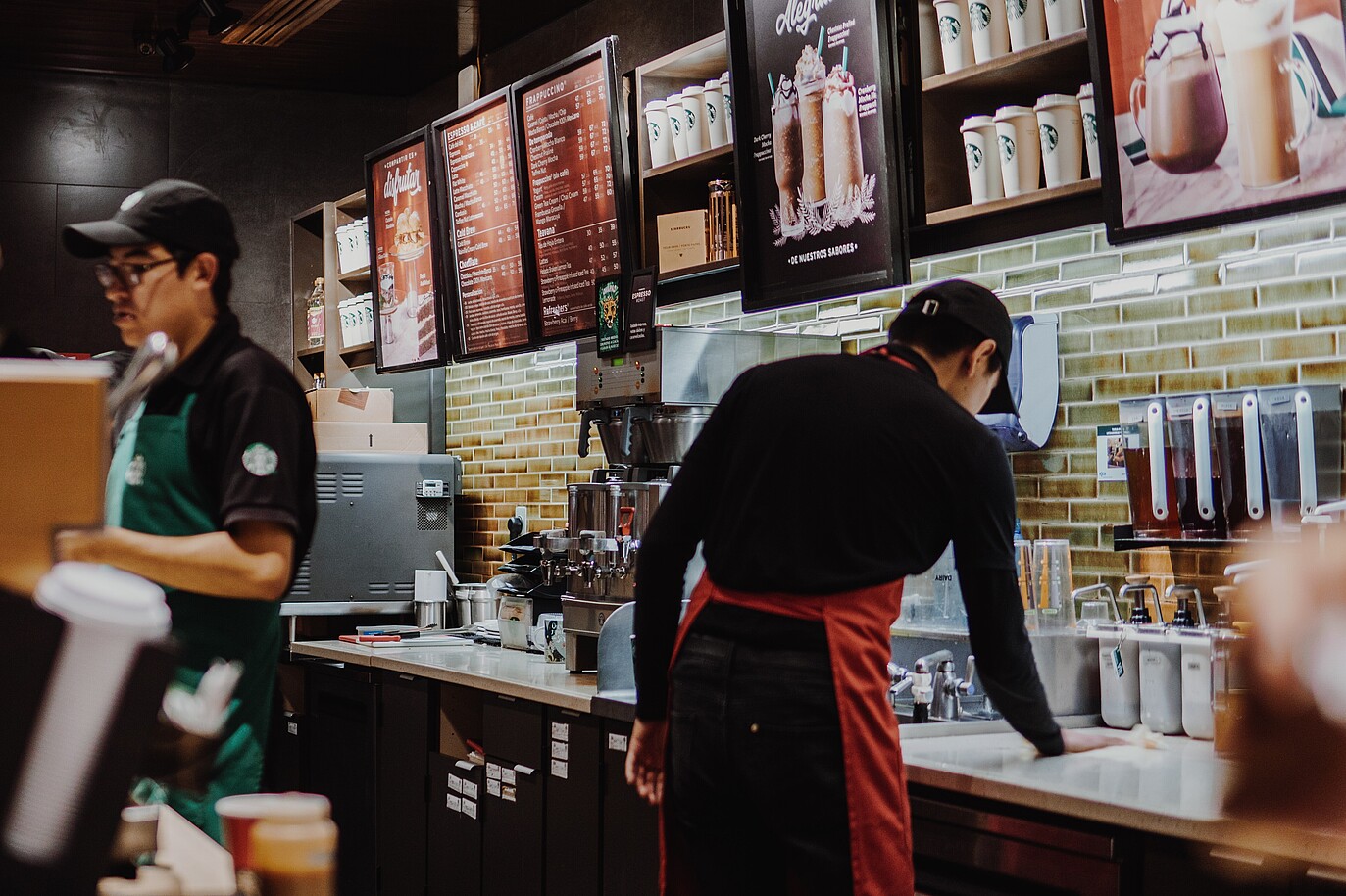 Starbucks employees actively working behind the counter, preparing orders and assisting customers.