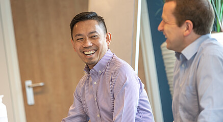 Two participants in the Rotterdam School of Management's classroom, sitting next to each other and laughing together