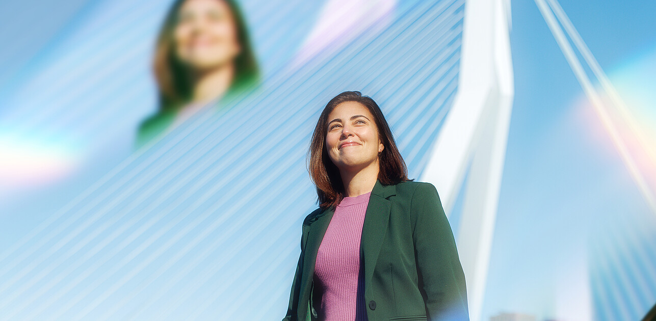 Een vrouw die voor de Erasmusbrug staat met prisma's om haar heen. 