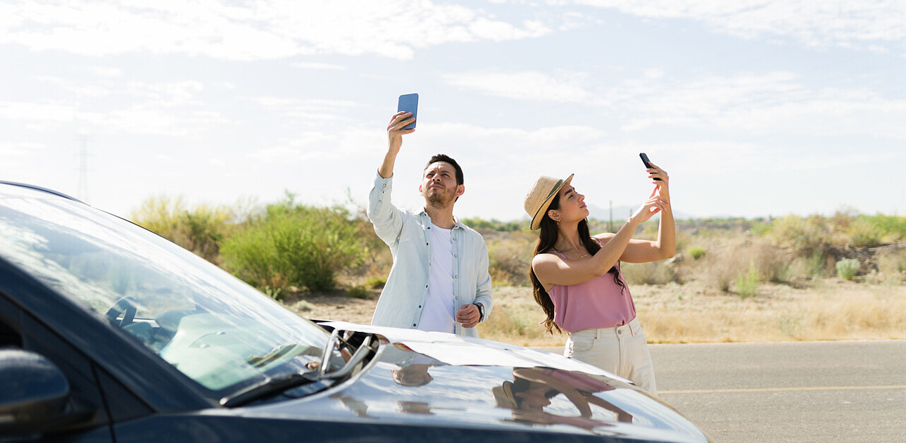 Two people looking for a signal on their phones