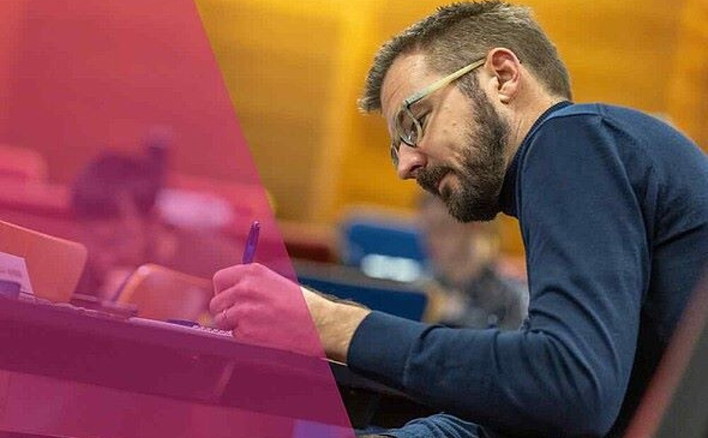 A male student focused on writing notes during an employee development programme at RSM.