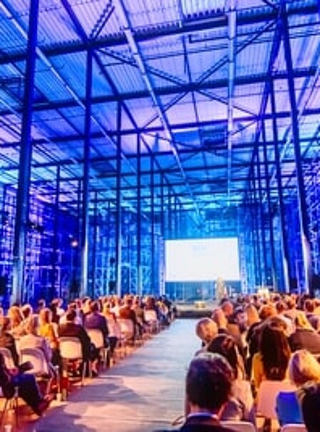 Leadership summit session in a contemporary conference room, with a captivated audience gathered to listen to a prominent leader's presentation.