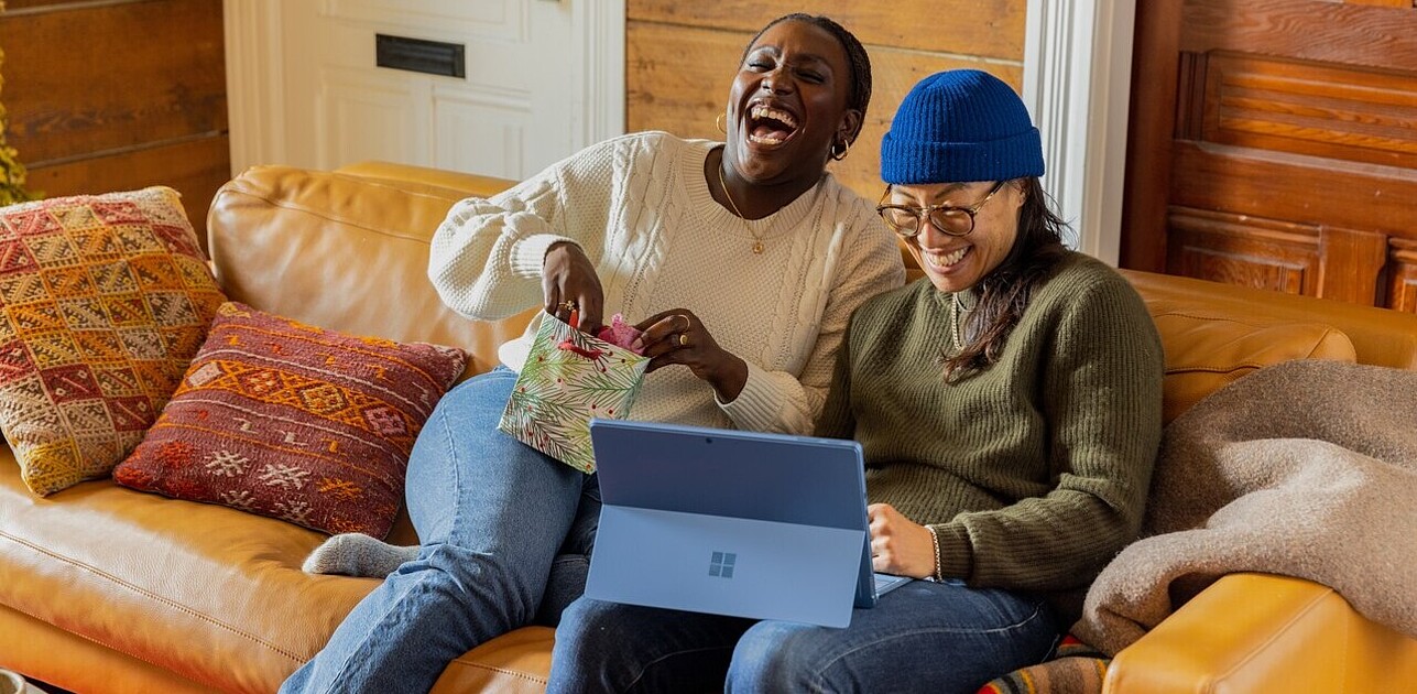 Two people laughing together whilst sitting on a couch