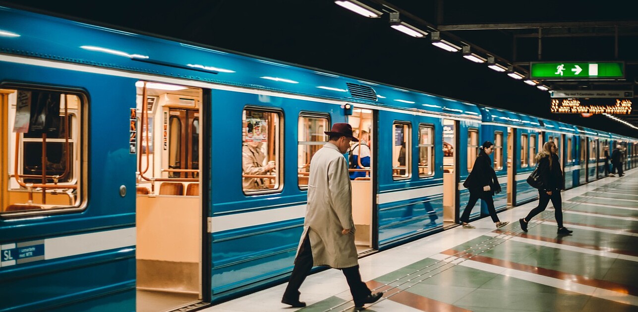 Passengers disembarking from a train onto a quiet platform during off-peak hours.