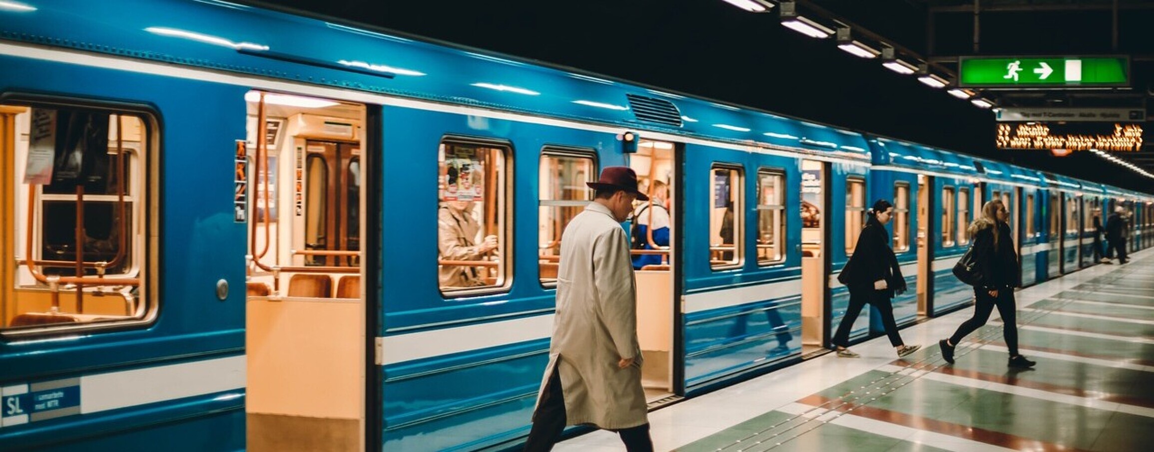 Passengers disembarking from a train onto a quiet platform during off-peak hours.