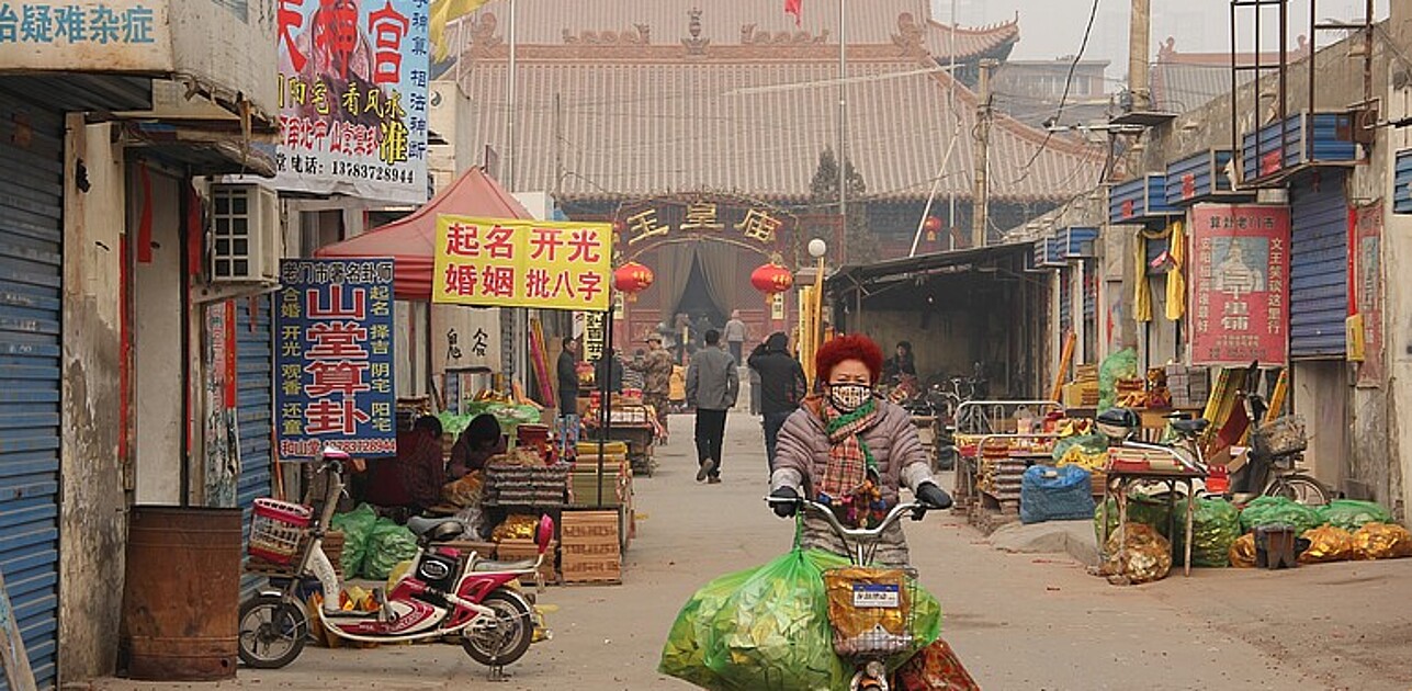 Woman with bags on bicycle in asia